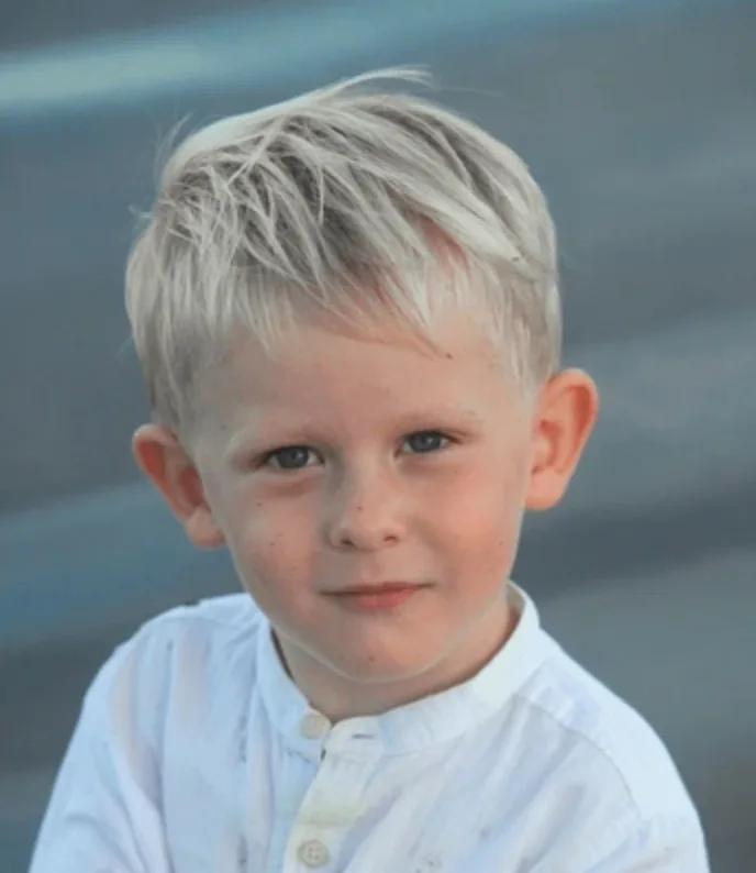 Photo of Aaron, a four-year-old boy with fair, tousled hair and blue eyes, in a white collarless shirt